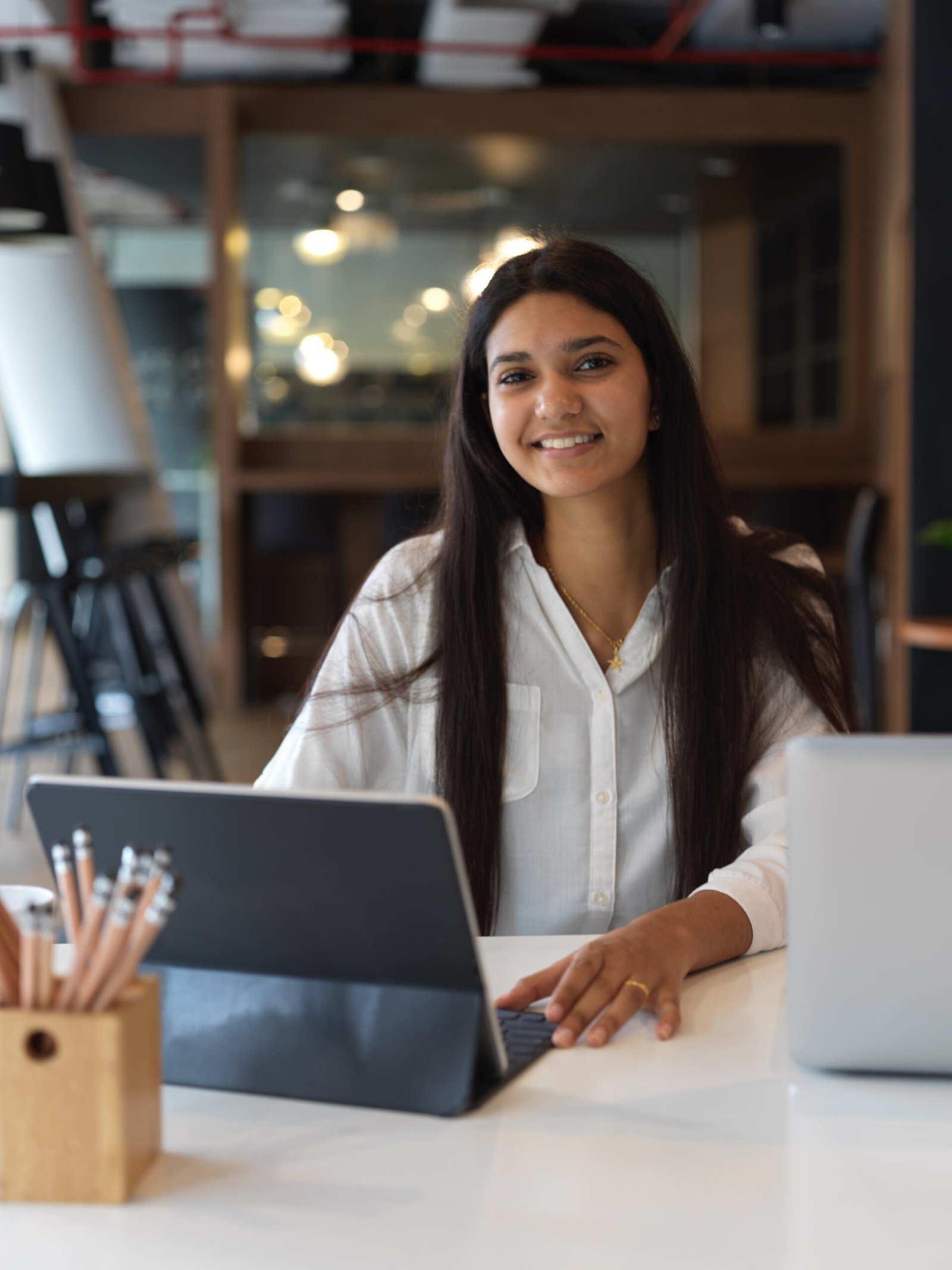 portrait of female teenager doing assignment with tablet in library