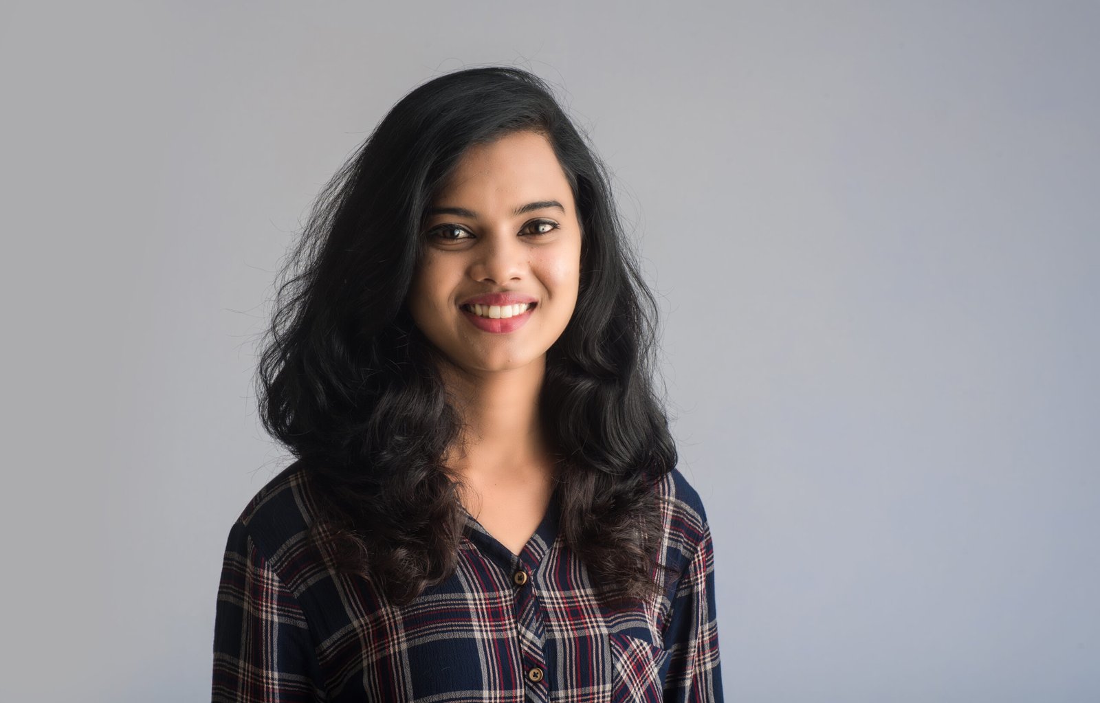 portrait of a young beautiful cute cheerful girl smiling looking at the camera on gray background